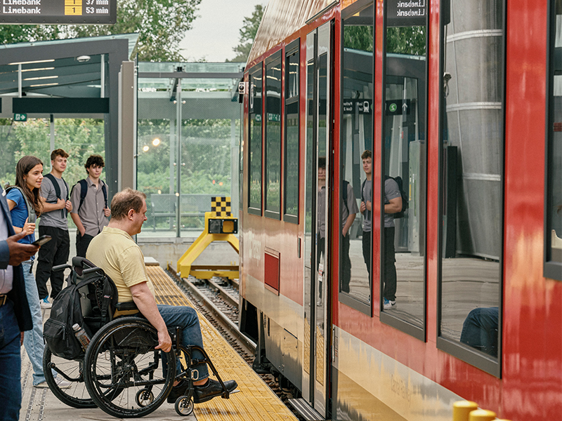 Une image d’un train LINT et d’un homme en fauteuil roulant qui attend d’y entrer