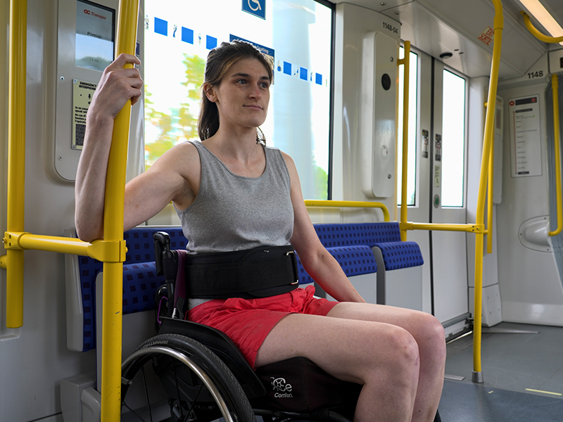 A woman in a wheelchair on the train holding a grab bar