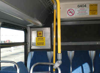 Boite d'alarme jaune avec un bouton route fixé au mur du fond de l'autobus