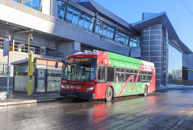 Side view of a green-and-red New Flyer XE40 electric bus