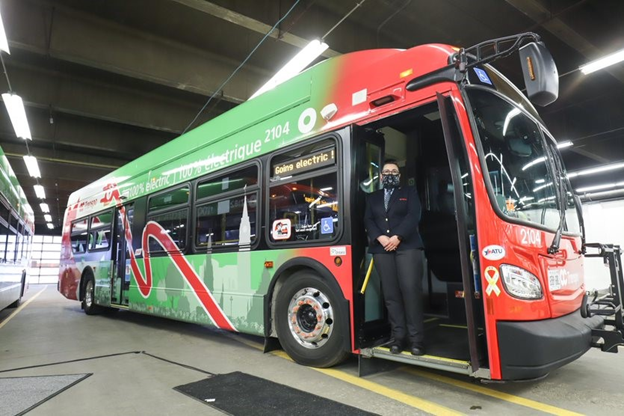 Personne portant l'uniforme de conducteur d'autobus debout à la porte d'un autobus électrique