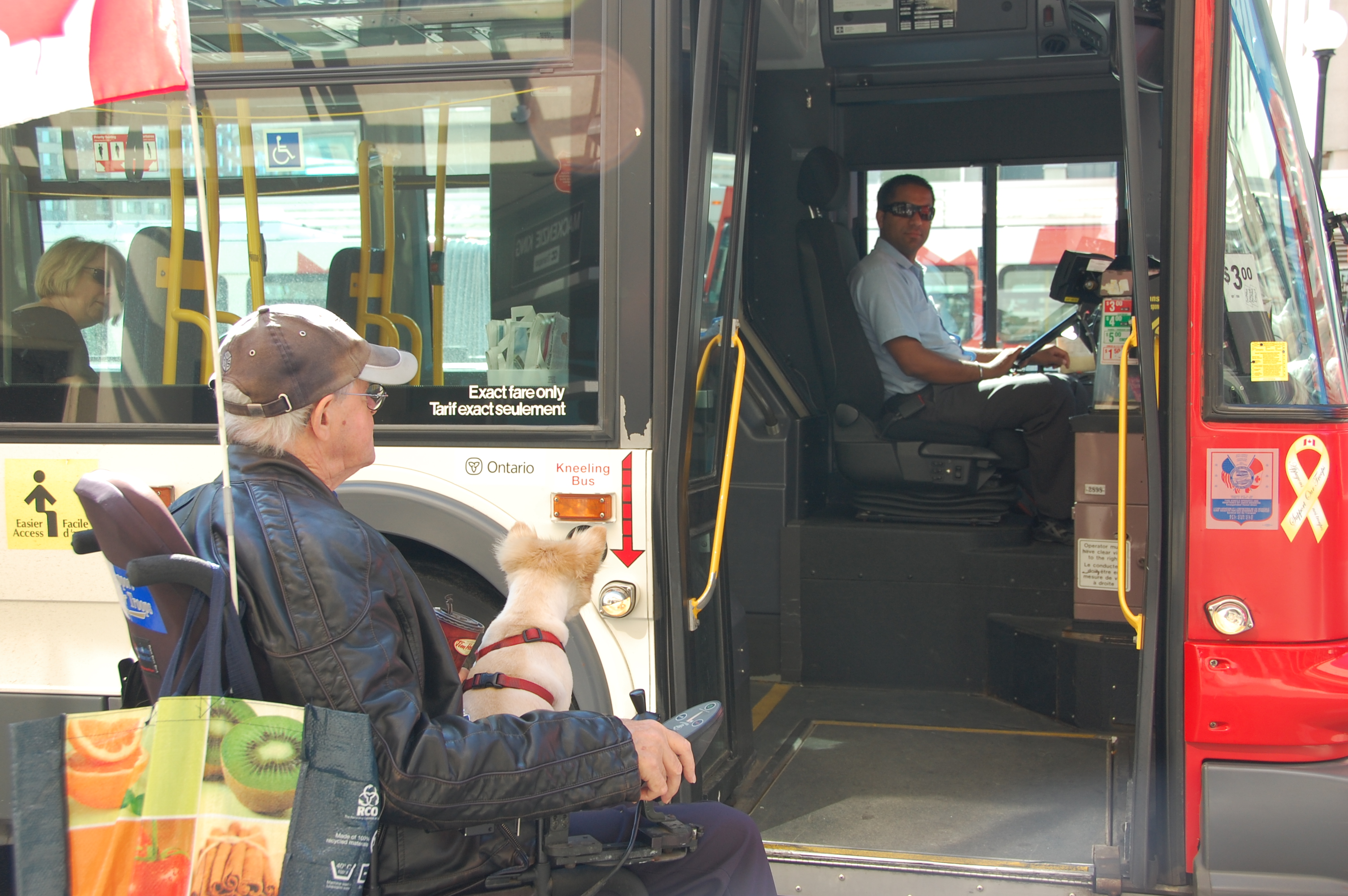 Mature rider in a wheelchair boarding a low-floor (kneeling) bus